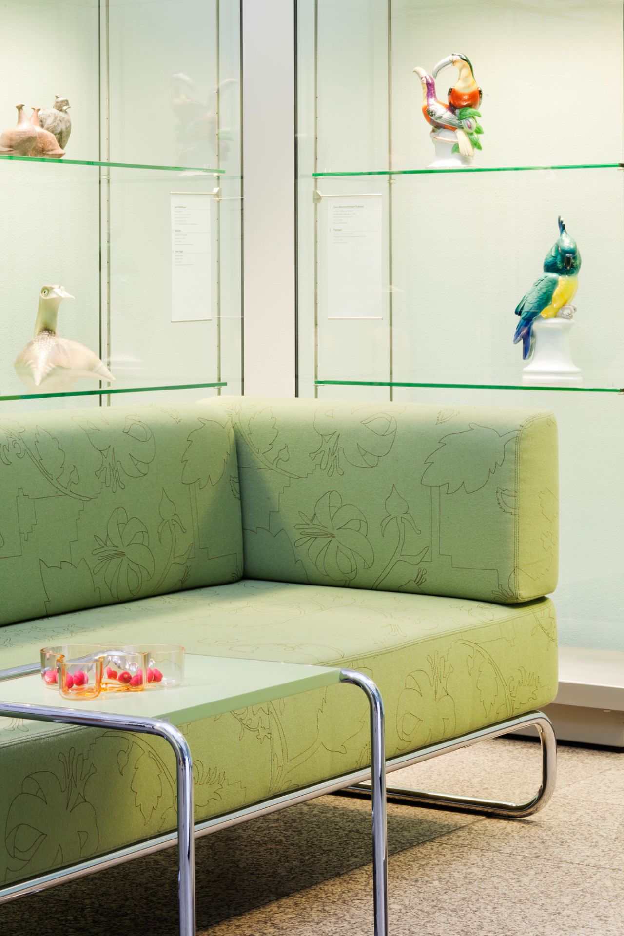 B97 Thonet Beistelltisch mit verchromtem Stahlrohrgestell und grüner Tischplatte vor einem grünen Sofa.