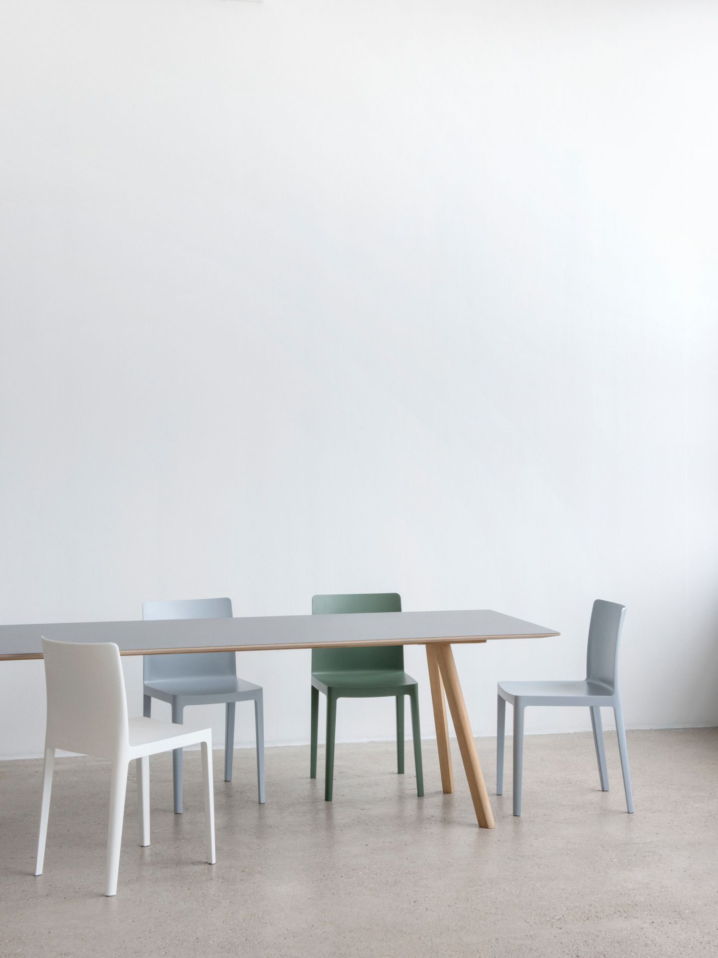 Copenhague Table CPH 30 Esstisch von Hay mit grauer Tischplatte und Holzbeinen, umgeben von Stühlen.