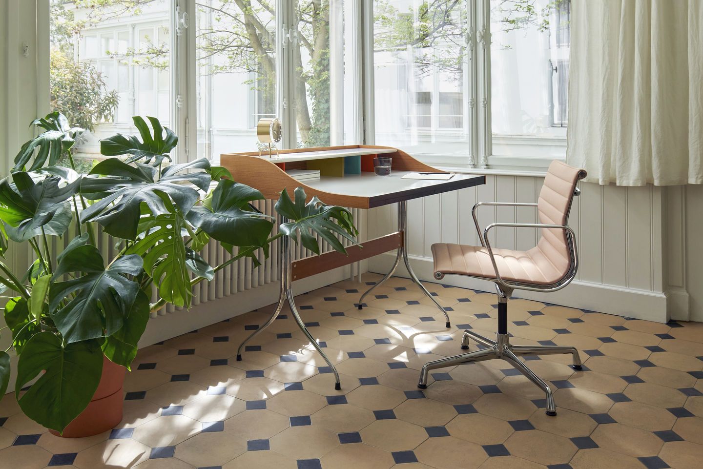 Vitra Aluminium Chair EA 104 in Rosé vor Schreibtisch mit Zimmerpflanze in hellem Raum.