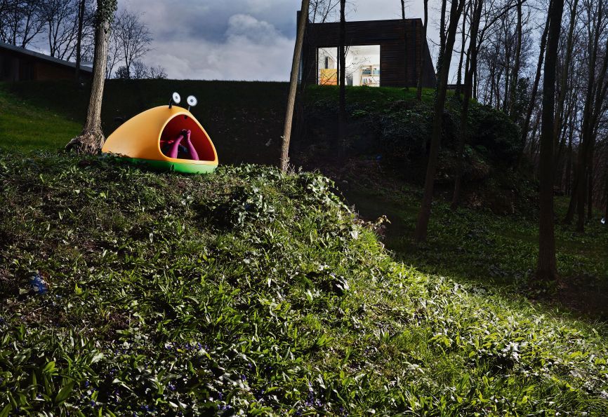 Gelbe Magis Nido Hõhle für Kinder im Garten, Füße ragen heraus, fantasievolles Spielhaus für draußen.