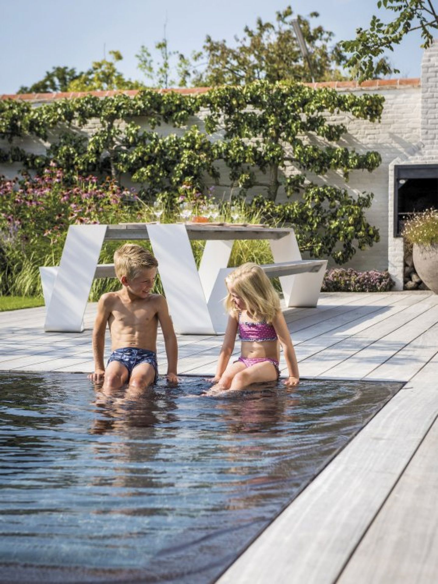 Hopper Picknickbank von Extremis im Garten mit spielenden Kindern am Pool.
