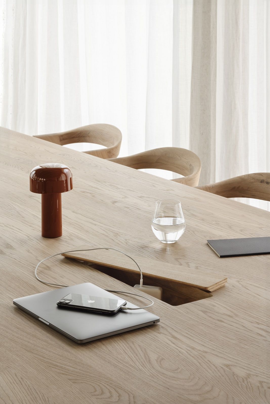 Detailaufnahme des Geometric Meetingtisches von Ethnicraft aus Eiche mit integrierter Kabelbox, Laptop und Smartphone.