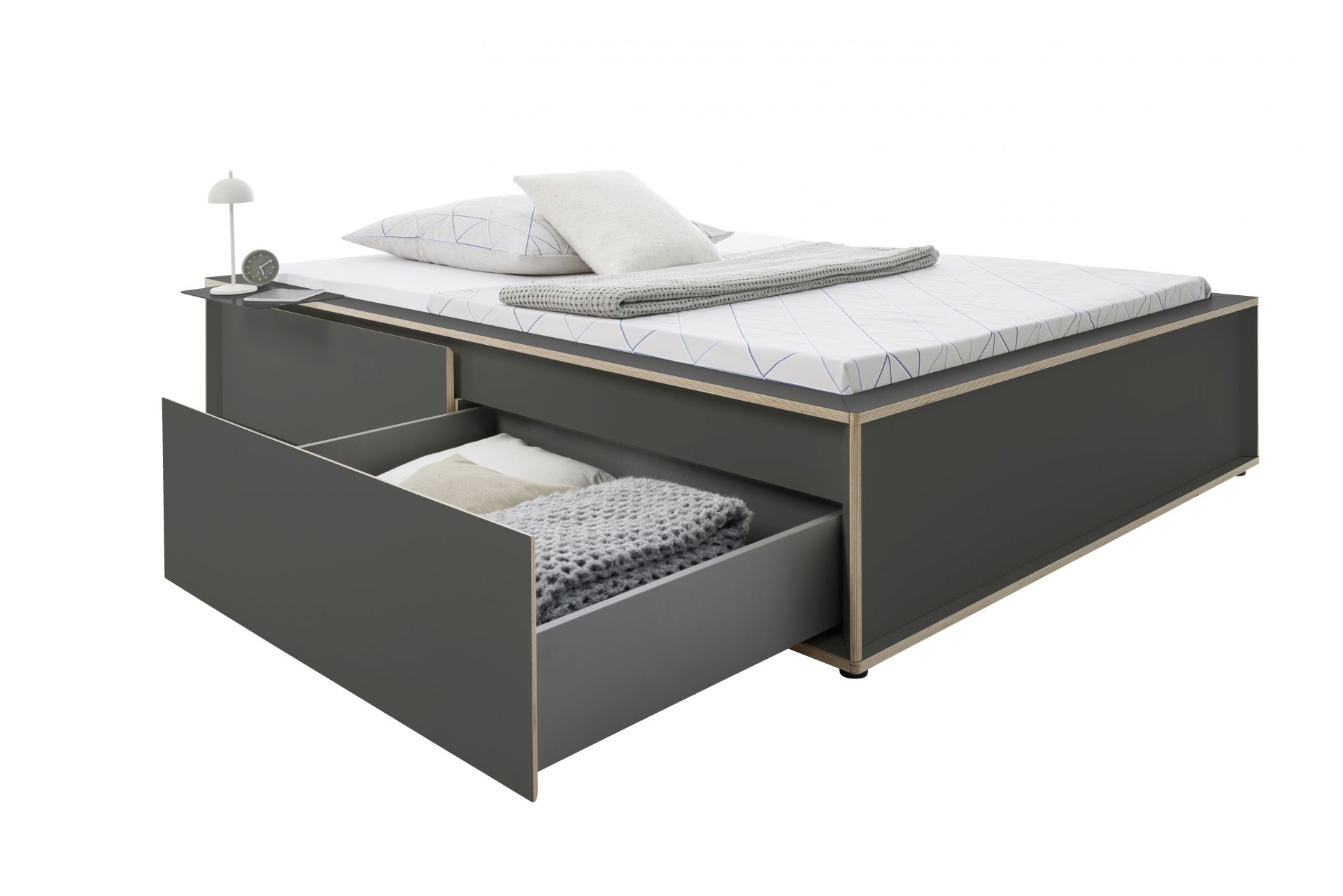 Spaze Bett von Müller Möbelwerkstätten in Grau mit Schublade, Nachttisch, Lampe, Kissen und Decke.