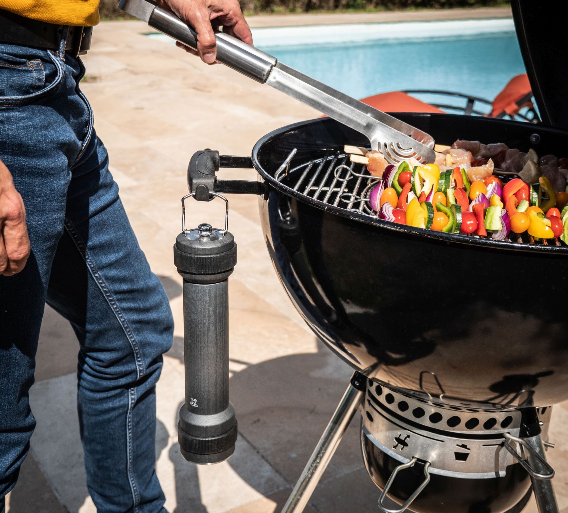 BBQ-Szene mit Grill, bunten Gemüsespießen und Peugeot Pfeffermühle in Graphit für das perfekte Grillaroma.