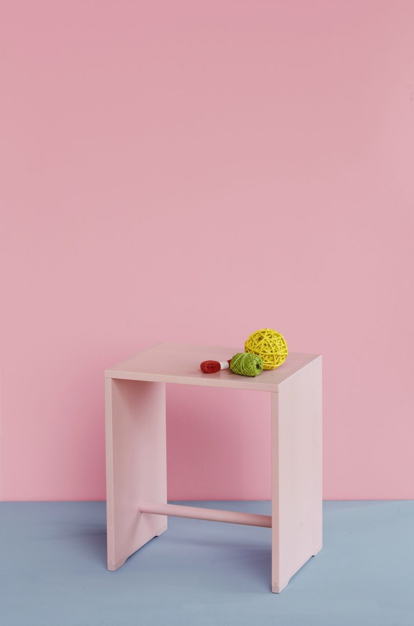 Rosa Ulmer Hocker Max Bill Limited Edition mit bunten Wollknäueln vor rosa Wand.