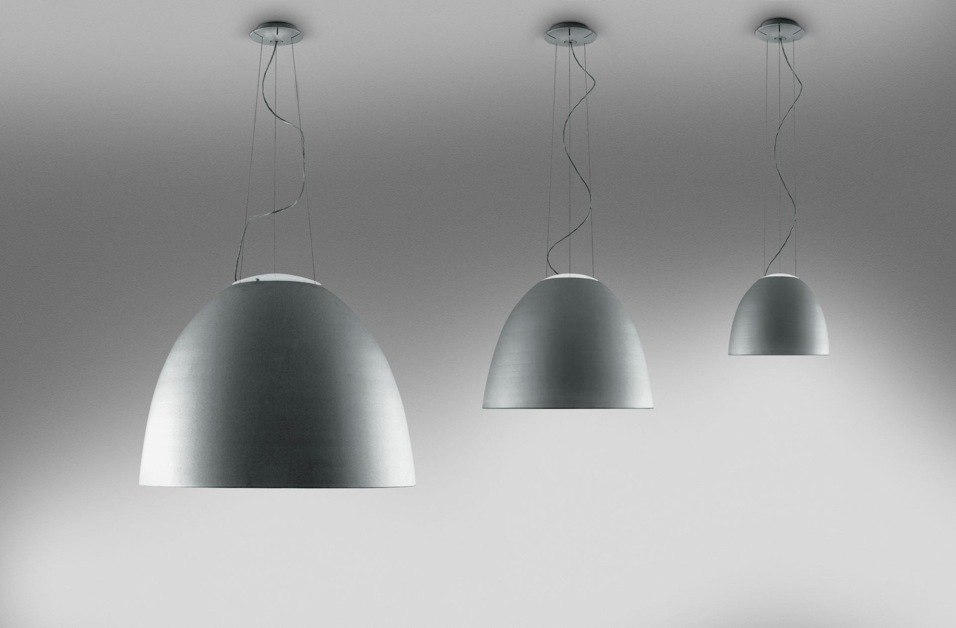 Drei silberne Artemide Mini Pendelleuchten in verschiedenen Größen hängen von der Decke.