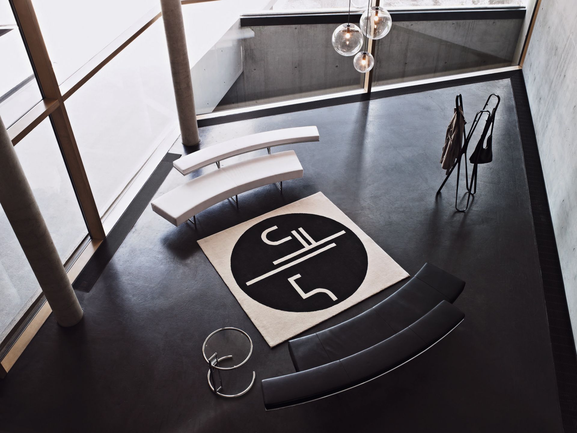 Luftaufnahme eines modern eingerichteten Raumes mit ClassiCon Adjustable Table E1027 Beistelltisch, Teppich und Sitzmöbeln.