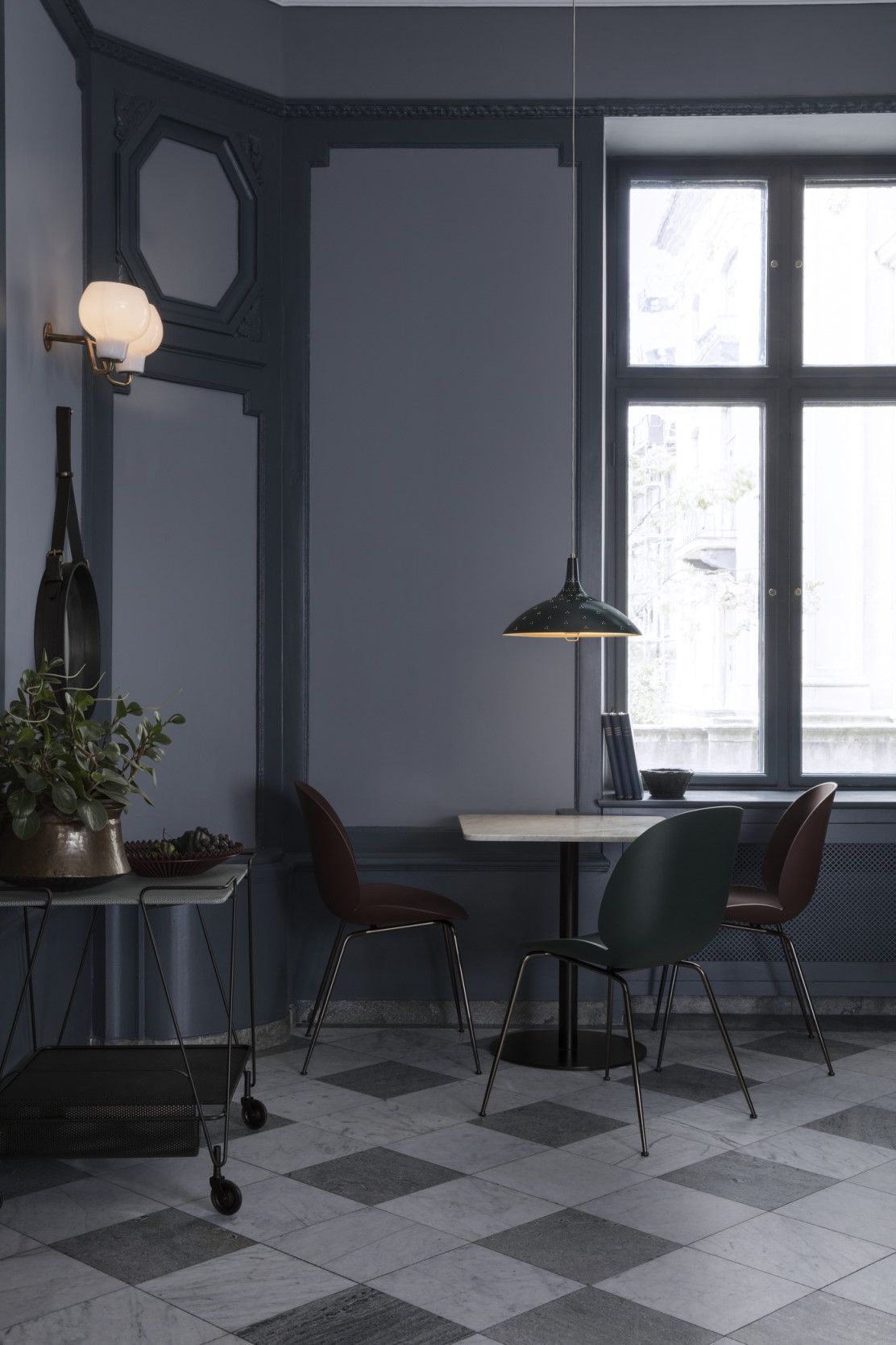 Esszimmer mit Gubi Pendelleuchte 1965 in Grün, minimalistischem Tisch und Stühlen. Designleuchte für stilvolle Beleuchtung.