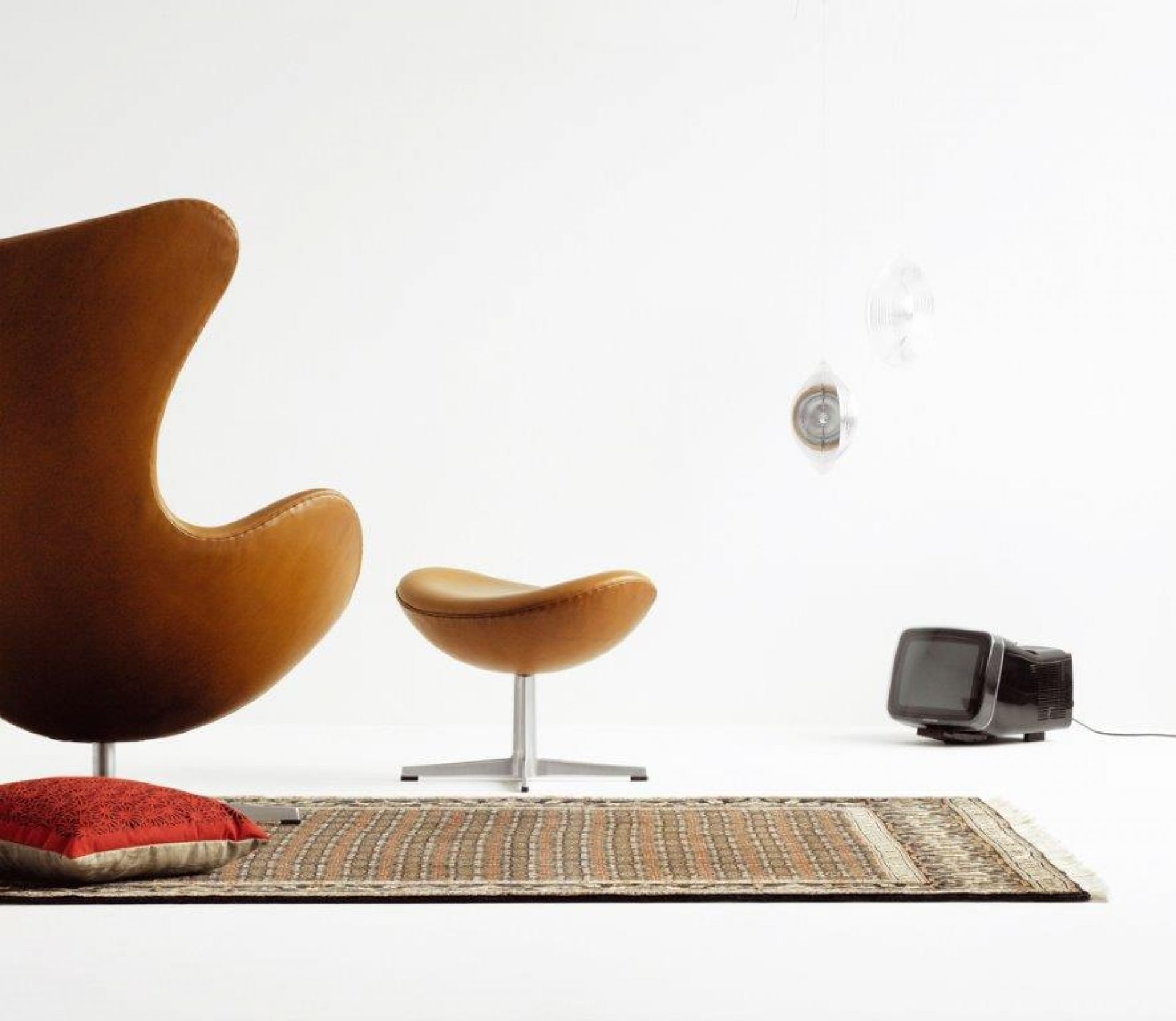 Brauner Egg Chair Sessel von Fritz Hansen mit passendem Hocker und Teppich in minimalistischem Ambiente.