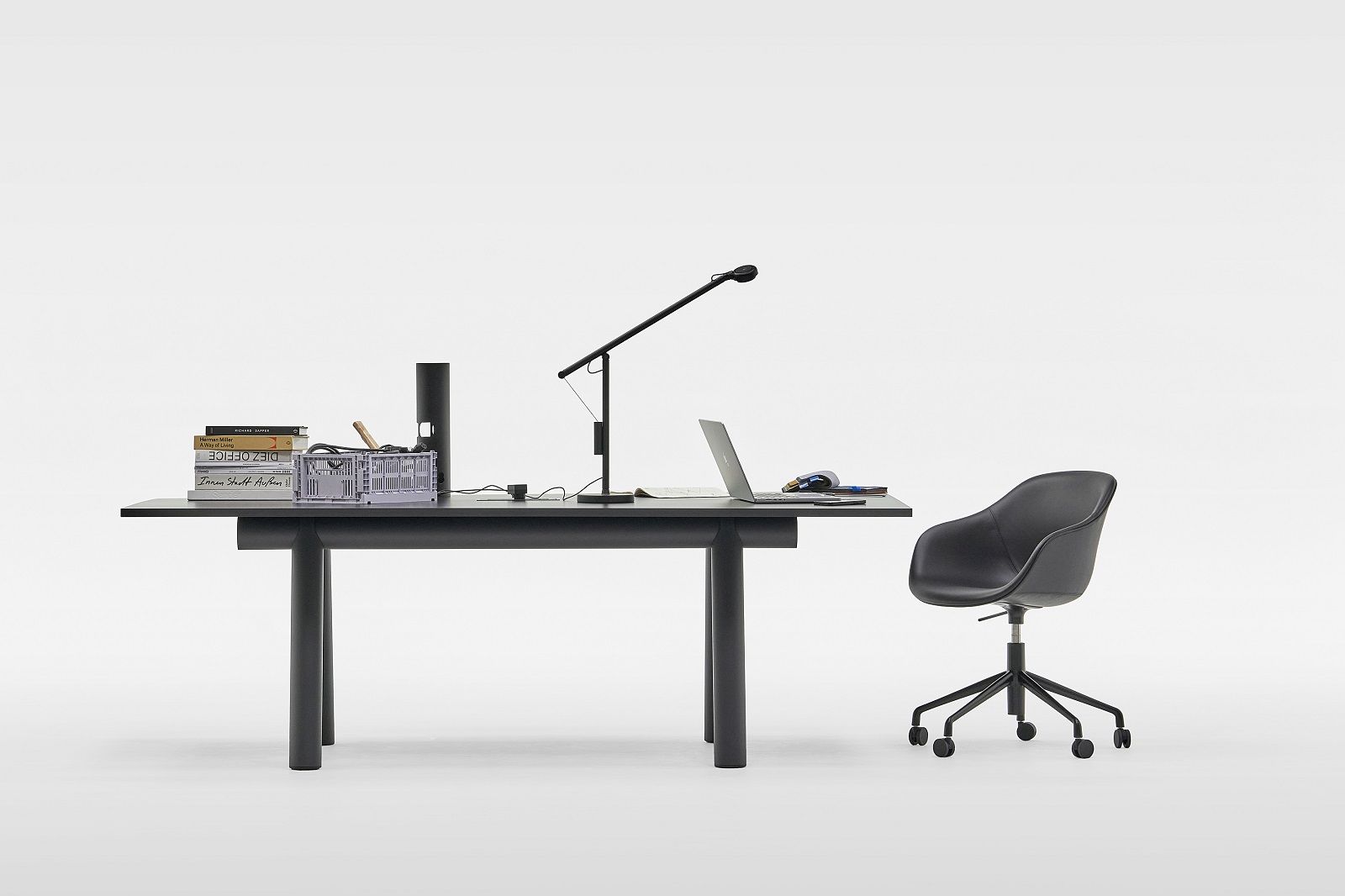 Schwarzer Hay Boa Table Tisch mit Büromaterialien und Bürostuhl vor weißem Hintergrund.