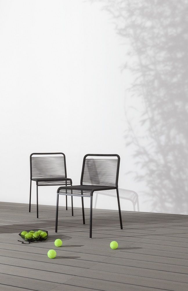 Zwei schwarze ARIA S42 Outdoor Stühle auf einer Terrasse mit Tennisbällen im Vordergrund.