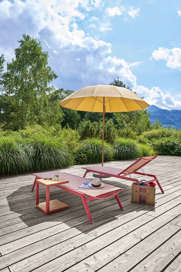 Beiger Weishäupl Pagodenschirm spendet Schatten über Liegen auf einer Holzterrasse im Garten.