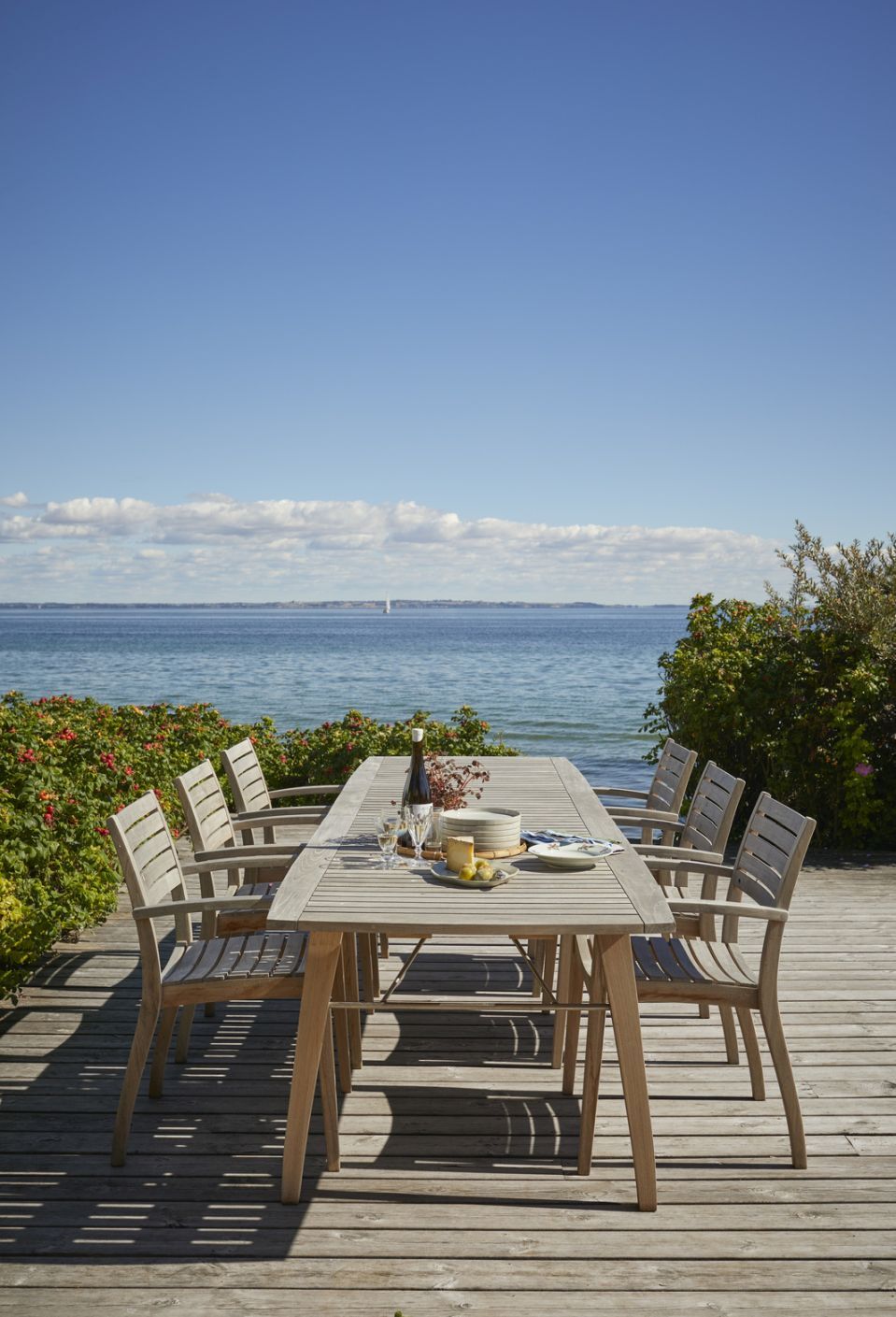 Ballare Chair Stuhl von Skagerak: Outdoor-Essbereich mit Holzstühlen und Tisch am Meer.