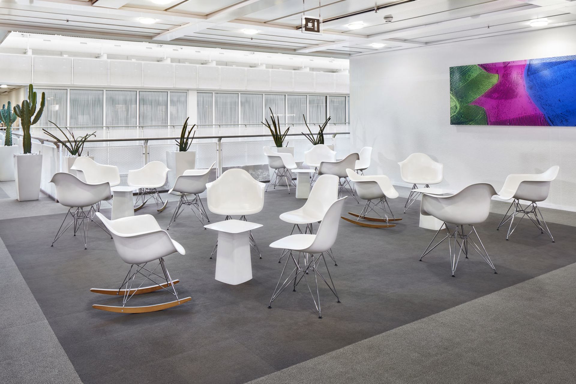 Helle Bürolounge mit Vitra Beistelltischen und Eames Plastic Chairs in Weiß, ideal für moderne Wartebereiche.