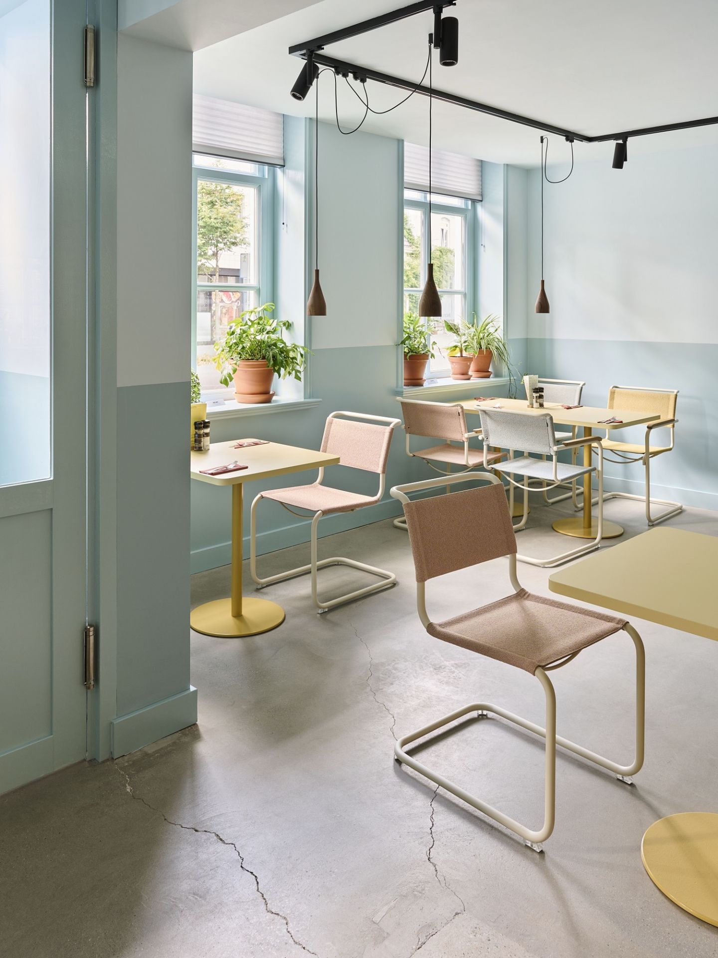 Innenraumansicht mit mehreren Thonet S 34 Freischwinger Stühlen und Tischen in einem hellen, modernen Ambiente.