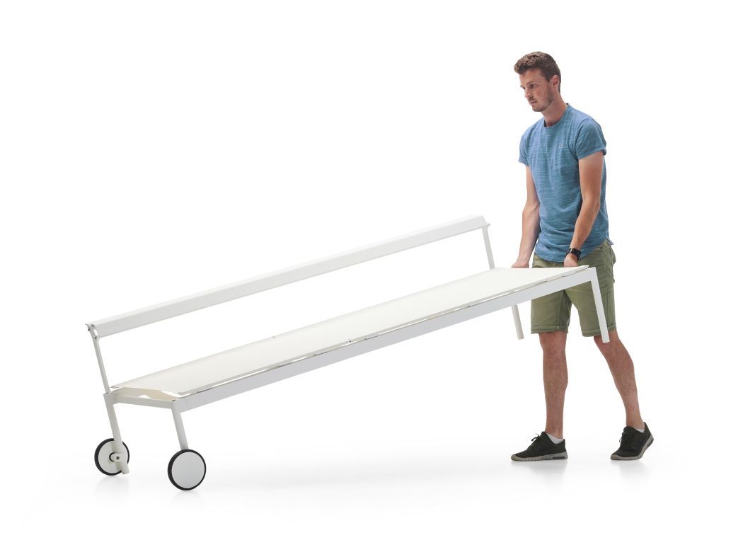 Mann transportiert weiße Sol + Luna Sonnenliege von Extremis mit Rollen für den Garten.