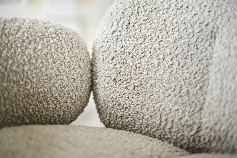 Detailaufnahme des Nana Armchair von Freifrau Manufaktur mit weichem, grauem Bouclé-Stoff für gemütliches Wohnen.