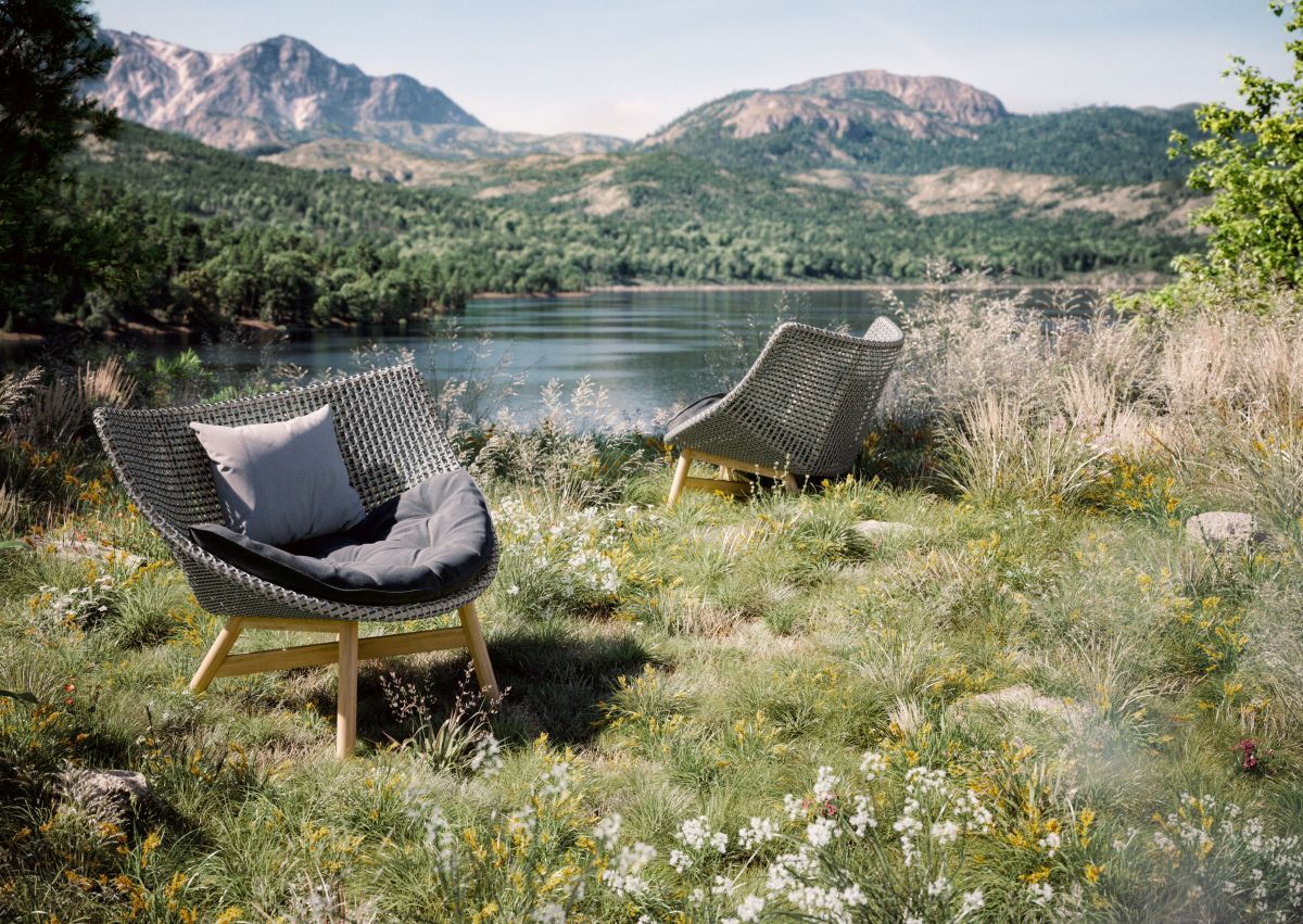 Mbrace Hocker von Dedon mit Polster im Freien, entspannter Outdoor-Sitzplatz mit Blick auf den See.