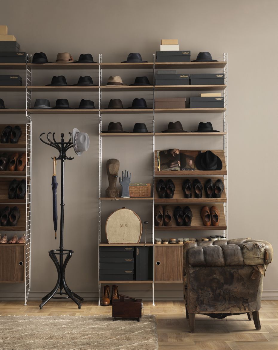 String Furniture Regalsystem mit Eiche-Holzböden, Hüten, Schuhen und Accessoires in einem stilvollen Ankleidezimmer.