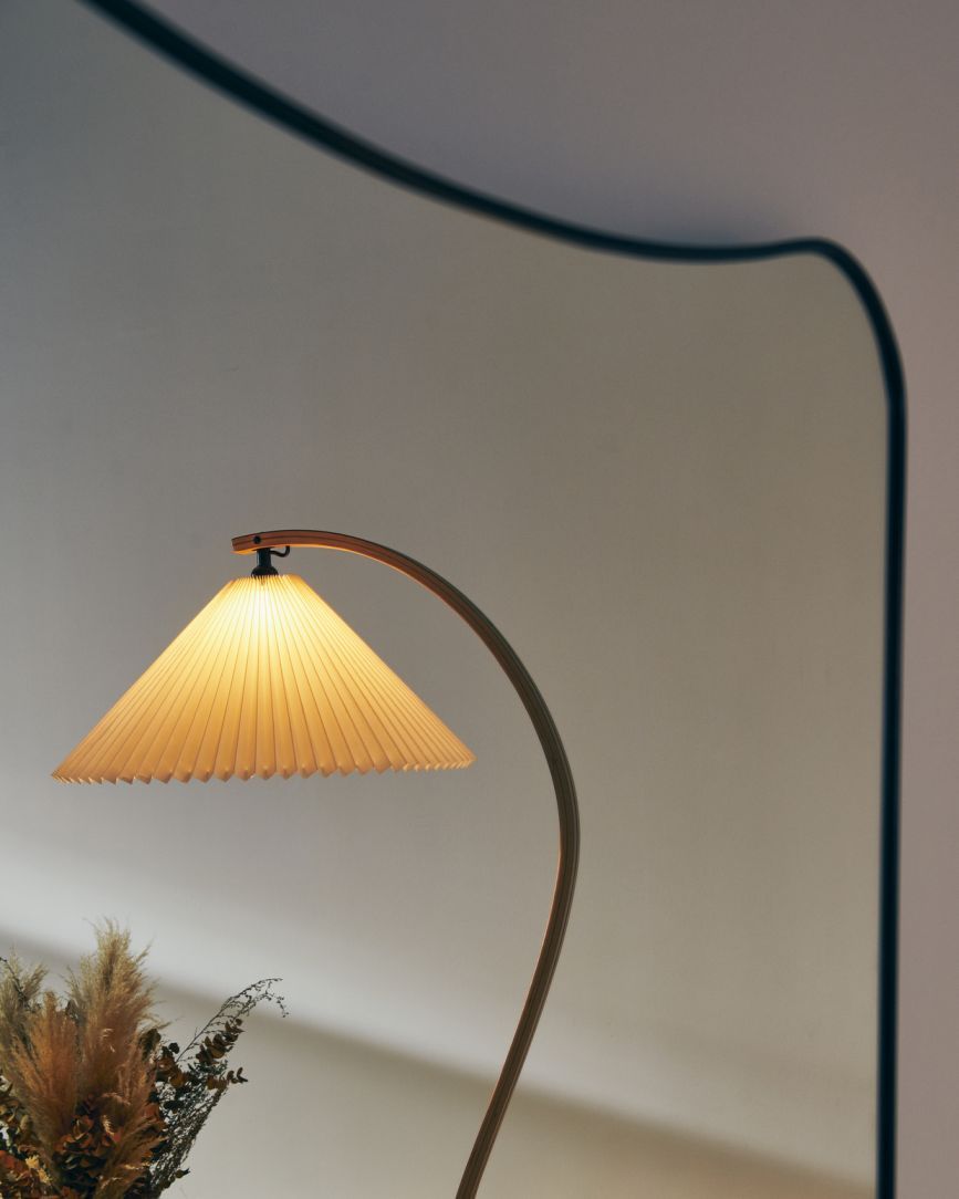 Elegante Timberline Stehleuchte von Gubi mit plissiertem Lampenschirm und gebogenem Holzfuß für stimmungsvolle Beleuchtung.