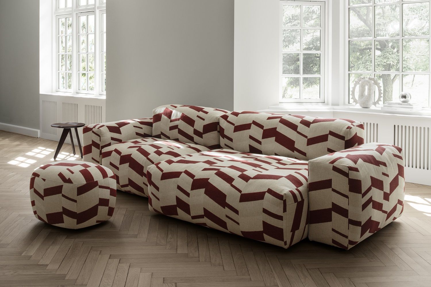 Norr11 Fin Beistelltisch aus dunklem Holz neben modularem Sofa mit geometrischem Muster in Wohnzimmer.