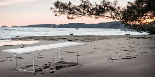 Weiße Bertoia Bank von Knoll International am Strand. Design Gartenbank für drinnen und draußen.