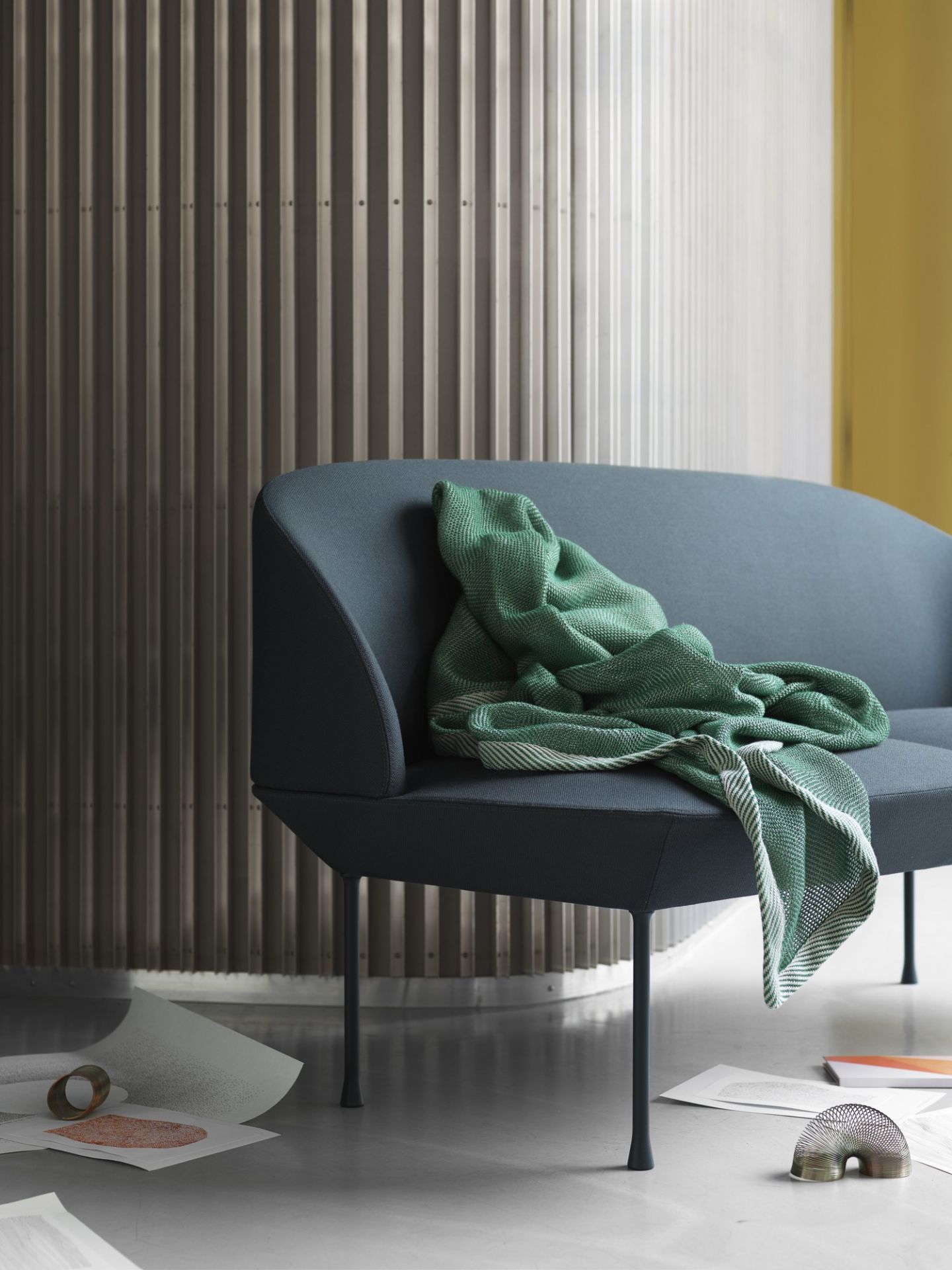 Nahaufnahme des Oslo Sofas von Muuto, ein blaues 2-Sitzer Sofa mit grüner Decke im modernen Wohnzimmer.