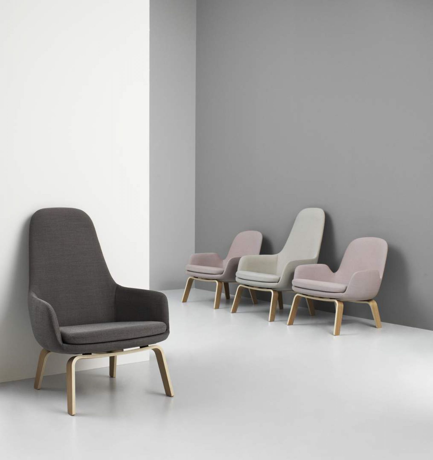 Grauer Era Lounge Chair Sessel niedrig von Normann Copenhagen mit Holzbeinen und weiteren Sesseln im Hintergrund.