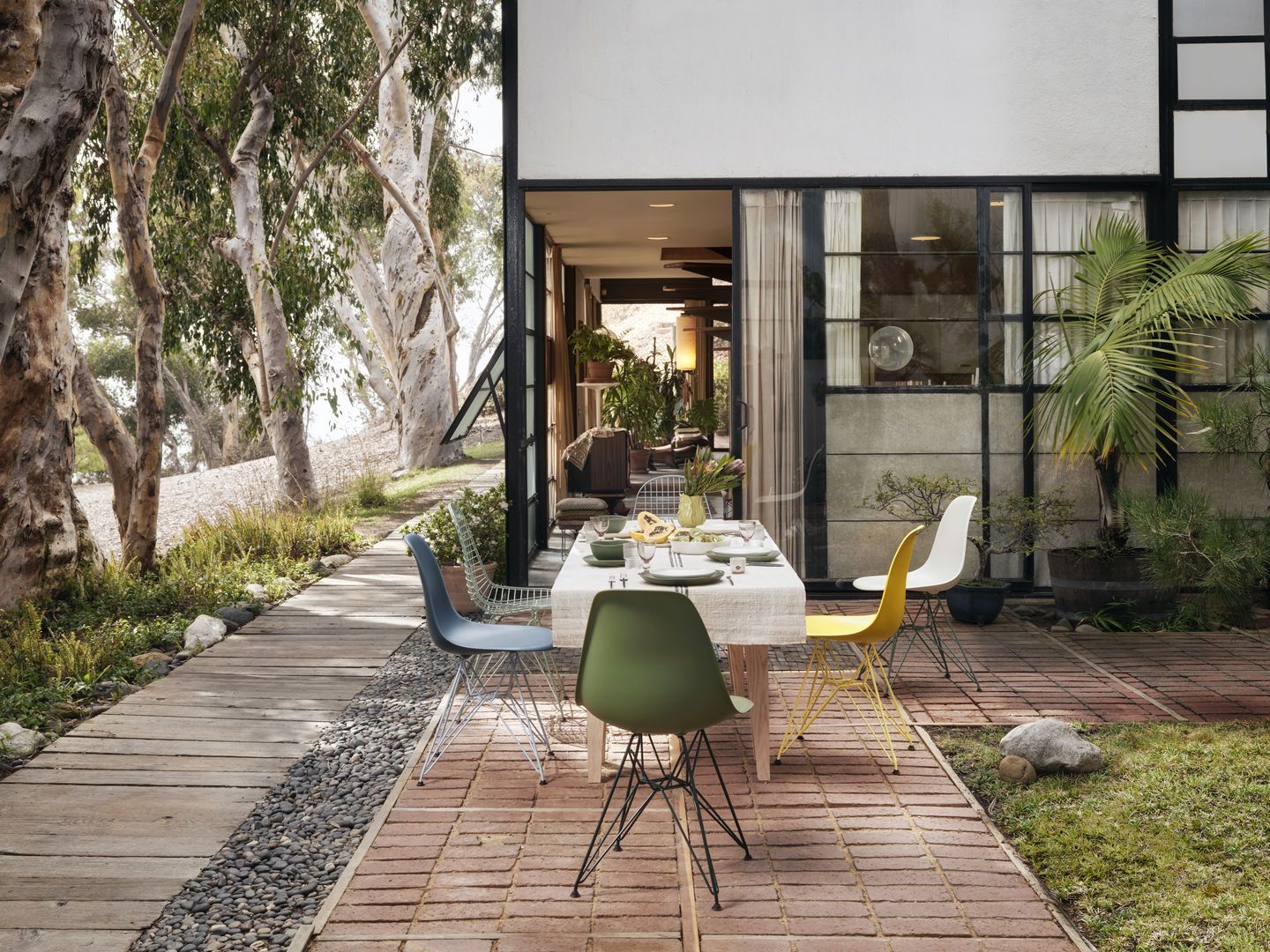 Eames Plastic Side Chair DSR Stühle von Vitra in verschiedenen Farben an Esstisch im Freien.