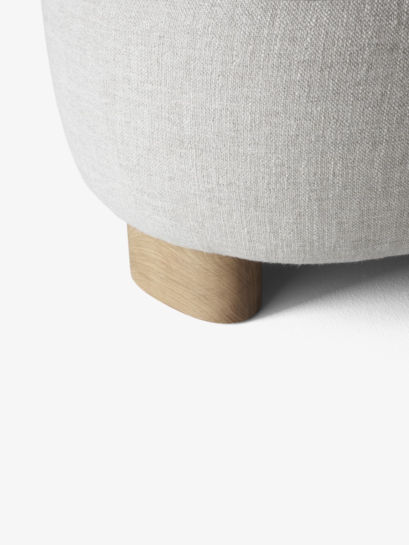 Detailaufnahme des Margas Loungesessels von AndTradition, der einen hellen Holzfuß und einen cremefarbenen Stoffbezug zeigt.