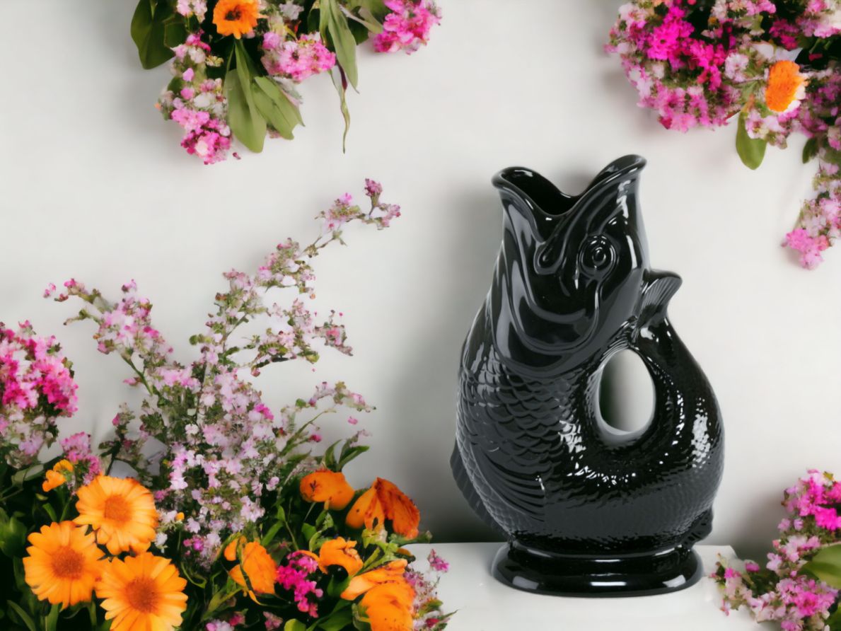 Schwarze Gluckigluck Fischkaraffe XL als Vase mit Blumenarrangement vor weißem Hintergrund.