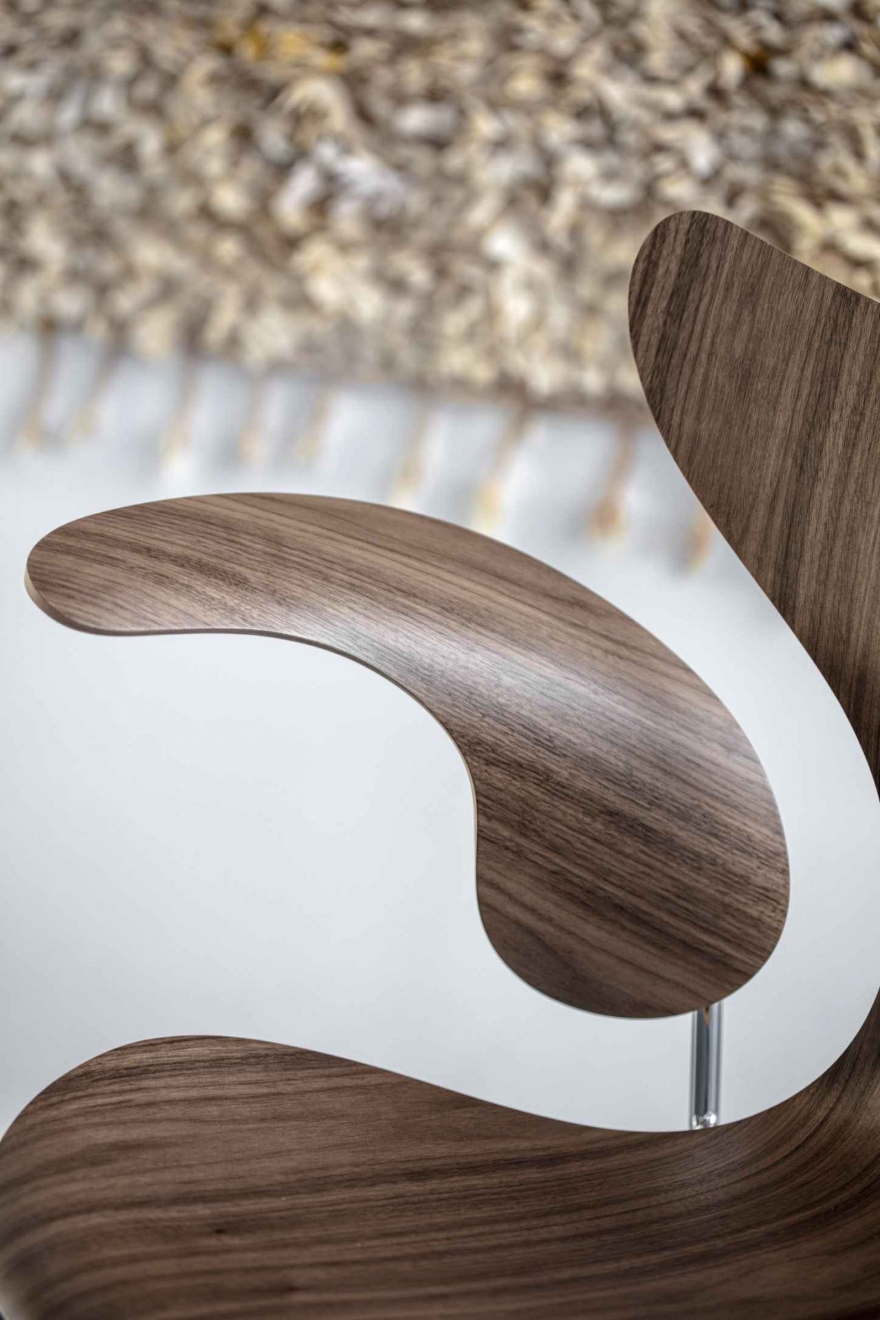 Detailaufnahme des Fritz Hansen Lily Armlehnstuhls 3208 mit Walnussholzfurnier und filigranem Chromfuß.