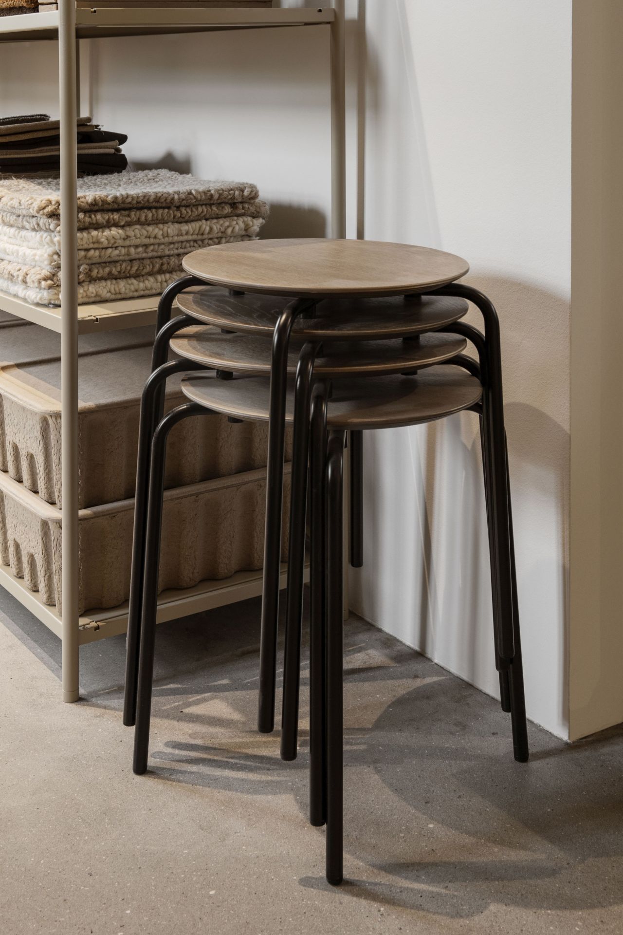 Stapelbare Herman Hocker von Ferm Living mit schwarzem Gestell und Holzplatte. Moderner Hocker für Wohnraum.