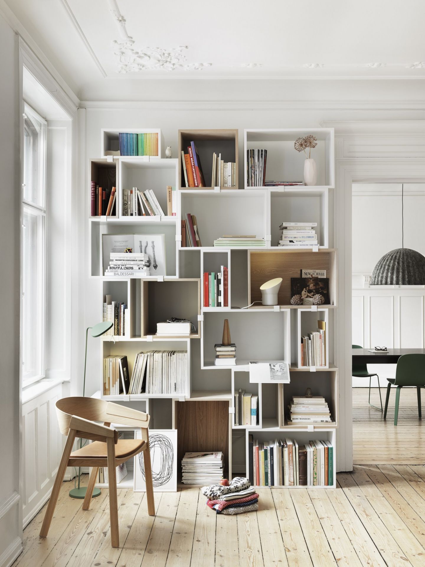 Muuto Stacked Storage System 2.0 Regalsystem in weiß und Holz, gefüllt mit Büchern und Dekoration.