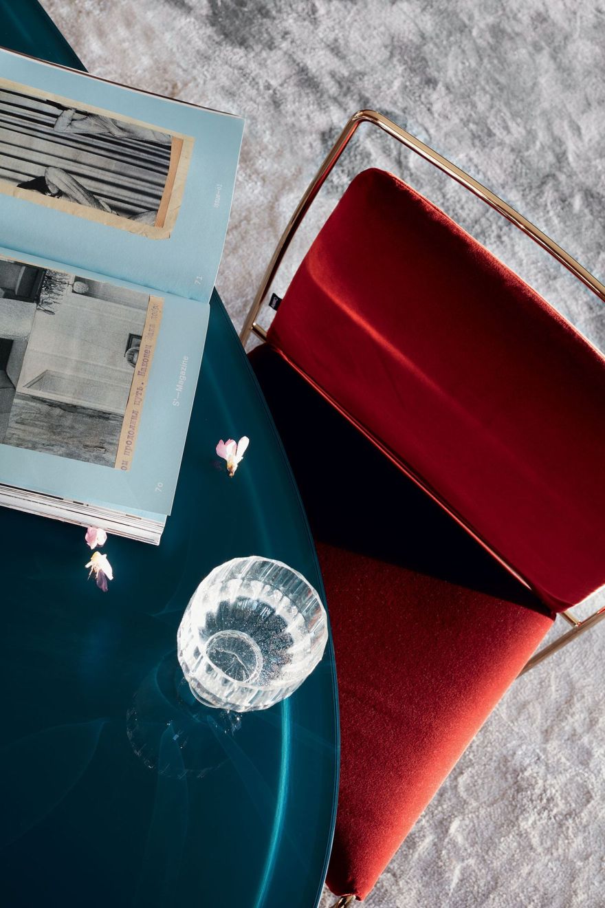 Nahaufnahme des Cassina Boboli Tisches mit Glas, Buch und rotem Stuhl. Designermöbel für stilvolles Wohnen.