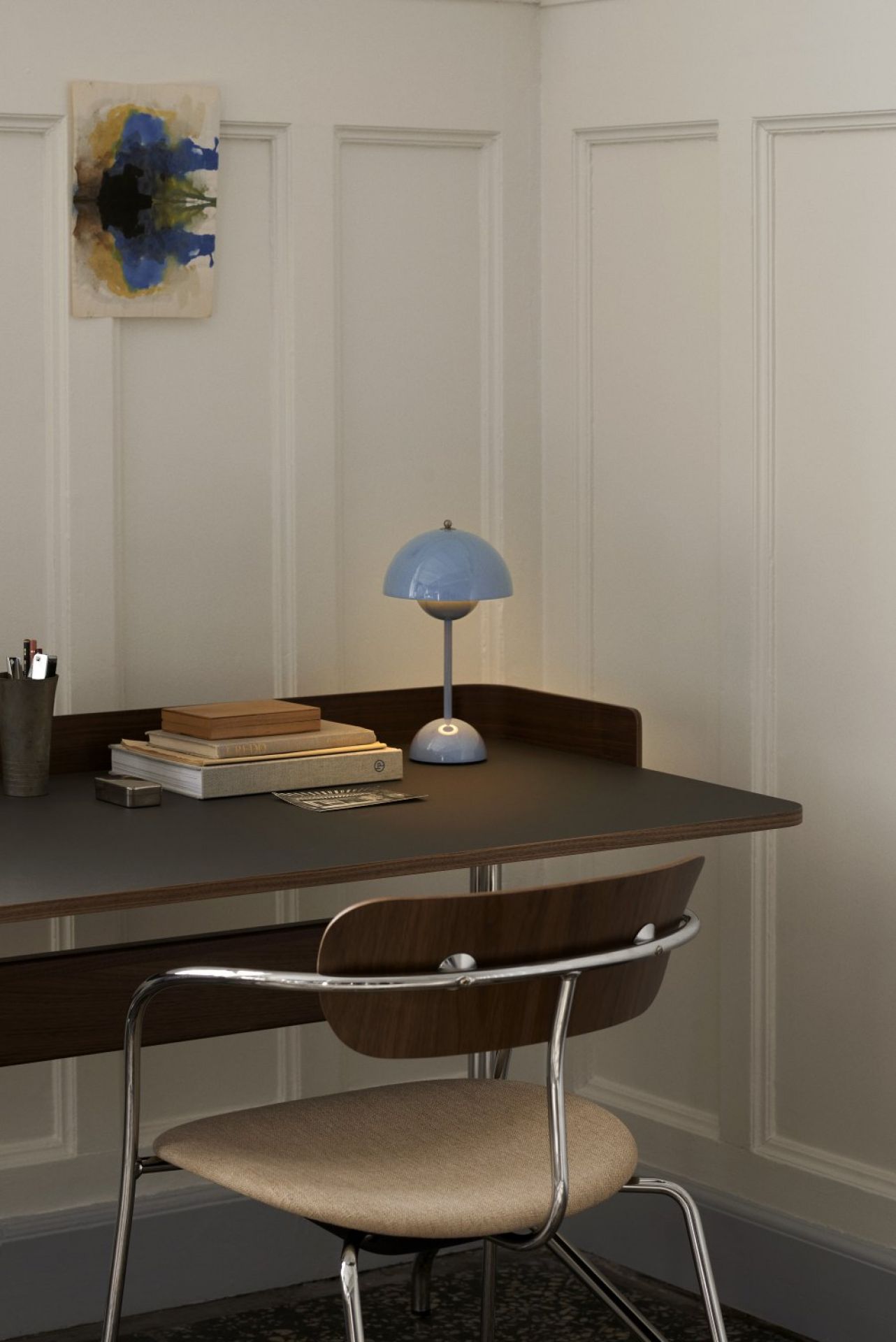 AndTradition Pavilion AV4 Armchair mit Sitzpolster vor Schreibtisch mit Lampe.