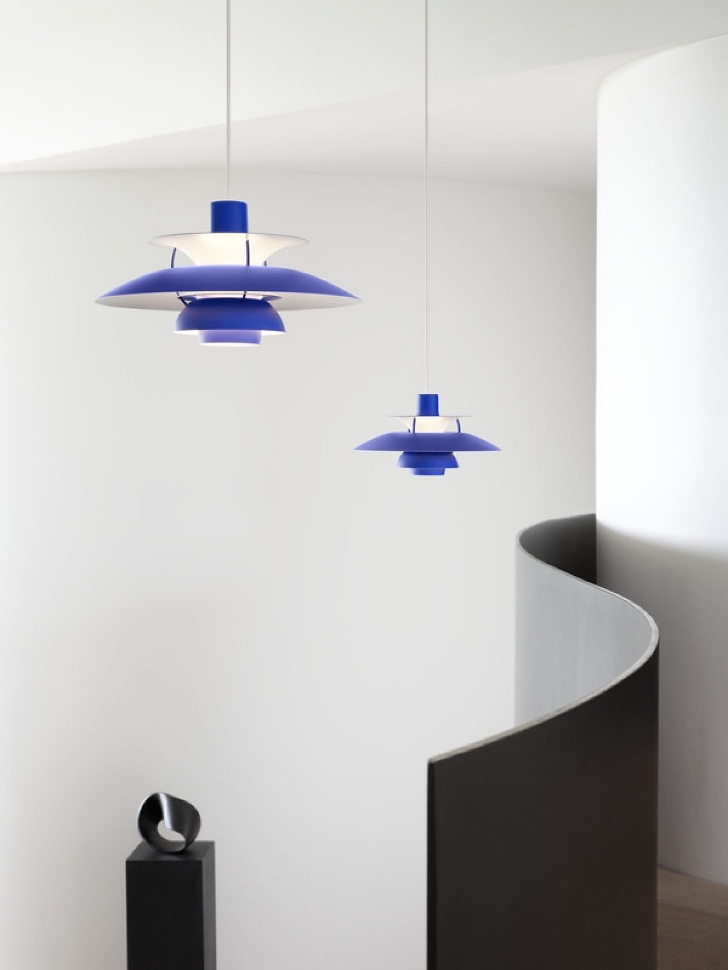 Zwei blaue PH 5 Mini Pendelleuchten von Louis Poulsen hängen in einem modernen Treppenhaus.