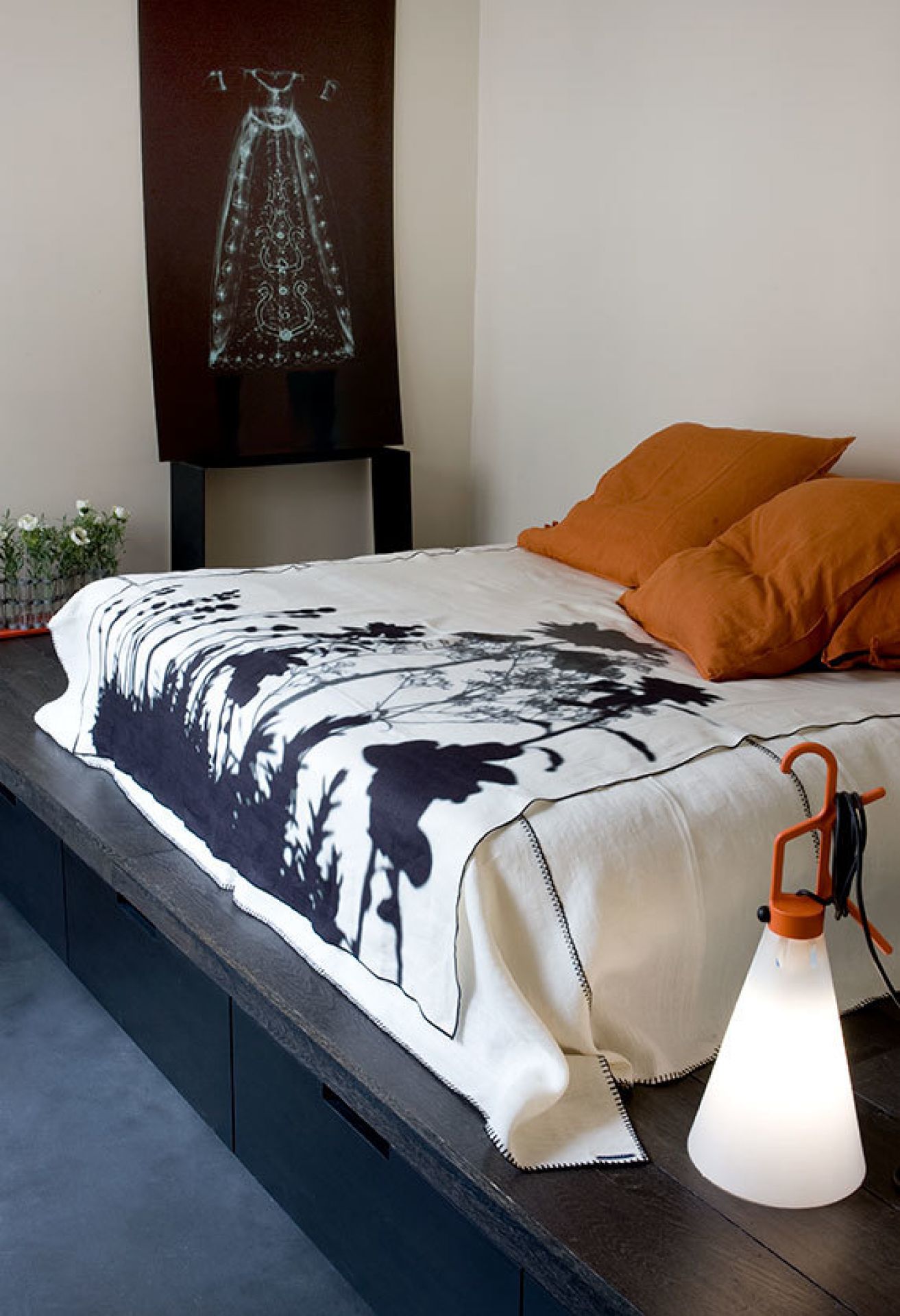May Day Leuchte von Flos neben Bett mit Decke und Kissen, modernes Wohnambiente.