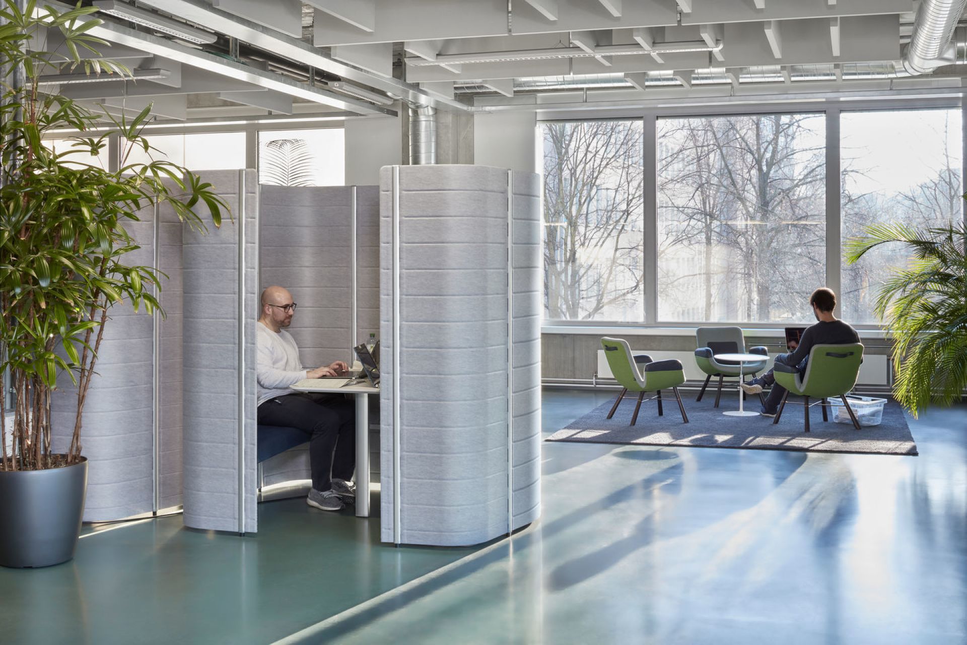Helles Büro mit East River Chair Sesseln von Vitra, Arbeitskabinen und großen Fenstern für moderne Büroeinrichtung.