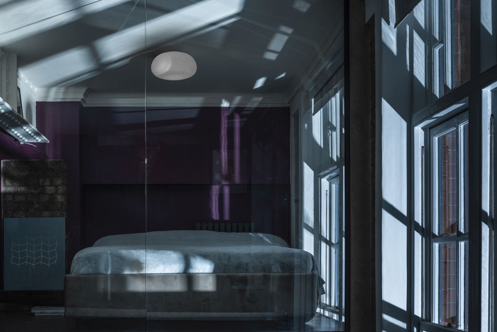 Schlafzimmer mit Bett und Rituals 2 Deckenleuchte von Foscarini, die ein warmes Licht spendet.