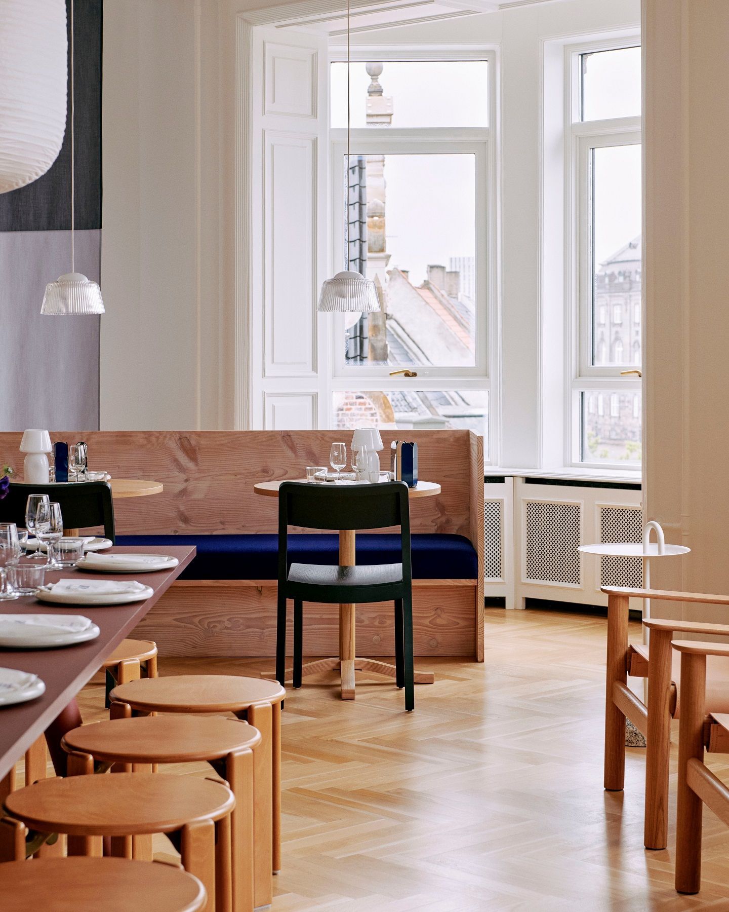 Innenaufnahme eines Restaurants mit mehreren Rey Stool Hockern von Hay aus Holz unter einem langen Tisch.
