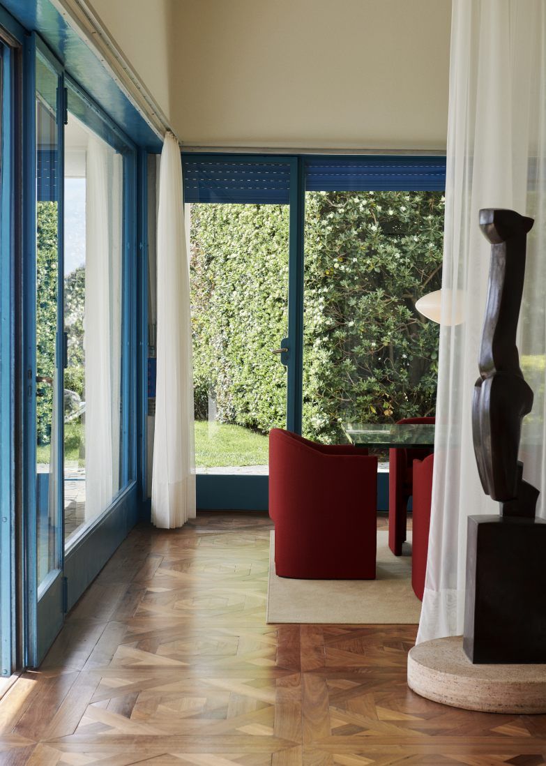 Esszimmer mit Mist AP15 Pendelleuchte von AndTradition, Opalglas-Hängelampe über Esstisch mit roten Stühlen.