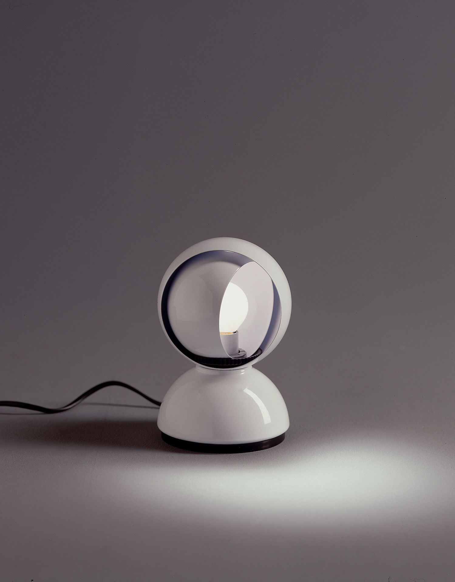 Weiße Artemide Eclisse Tischleuchte mit verstellbarem Schirm und warmem Lichtschein. Designklassiker für Tisch oder Wand.