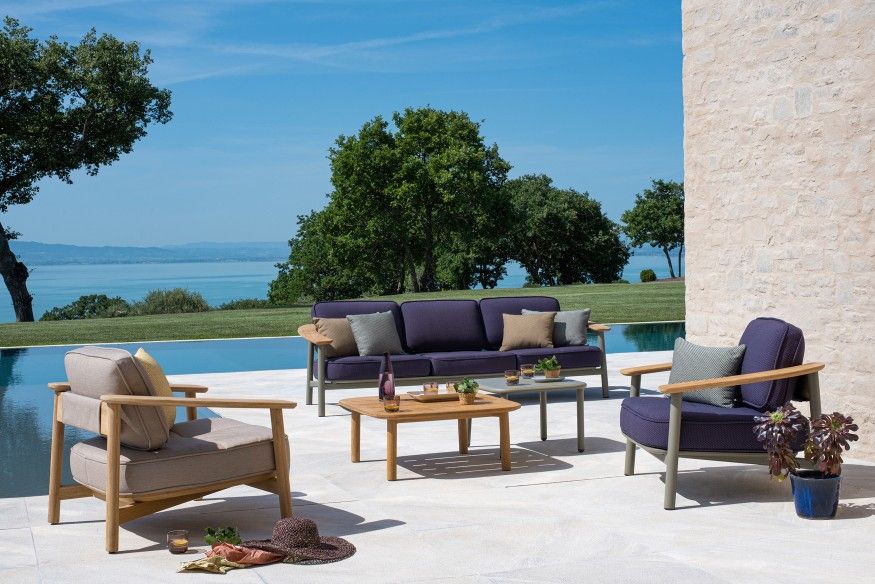 Emu Twins Outdoor Sofa und Sessel mit Couchtisch auf einer Terrasse mit Pool und Seeblick.