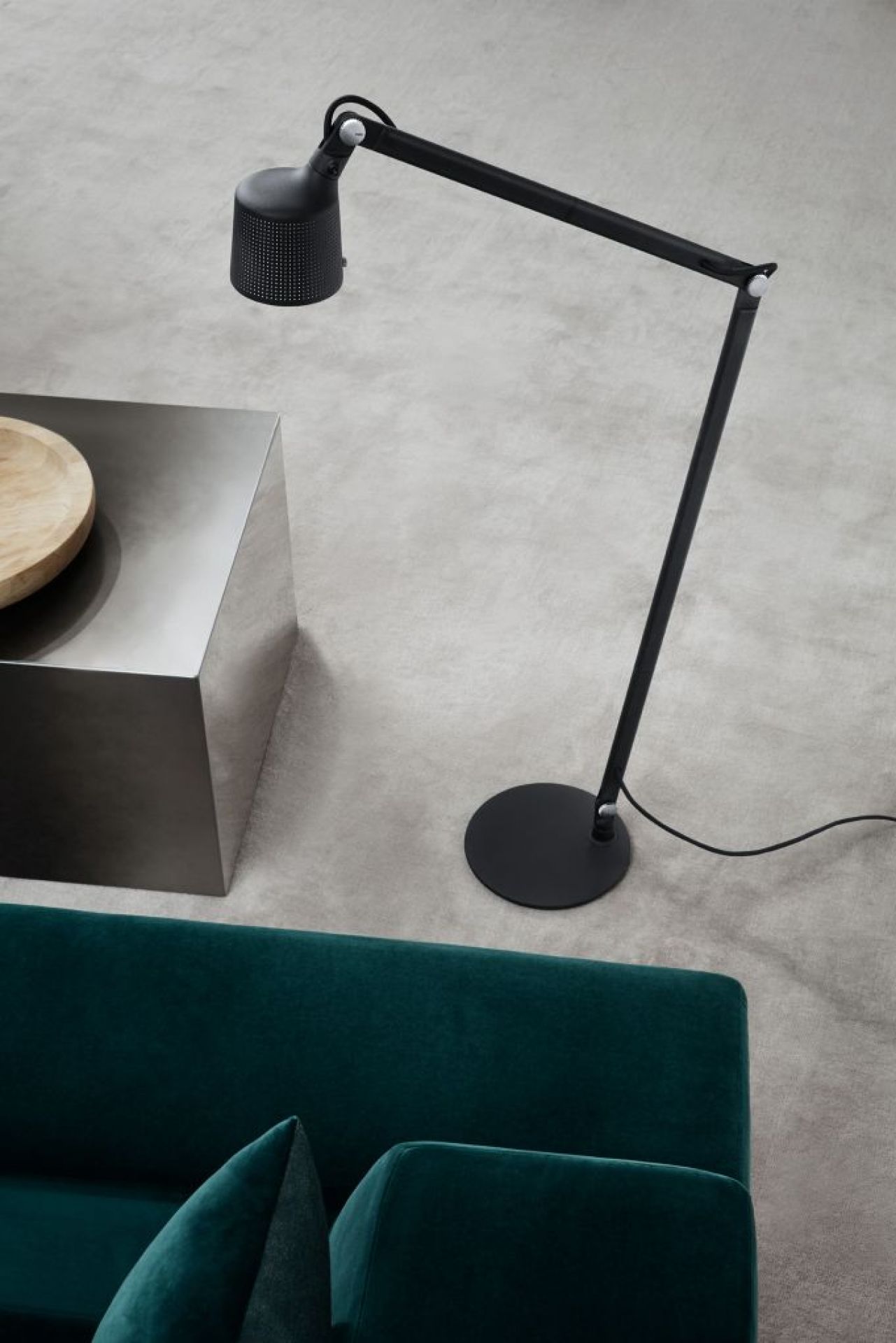 Schwarze Vipp Boden Leselampe mit verstellbarem Arm und perforiertem Lampenschirm neben Sofa und Beistelltisch.