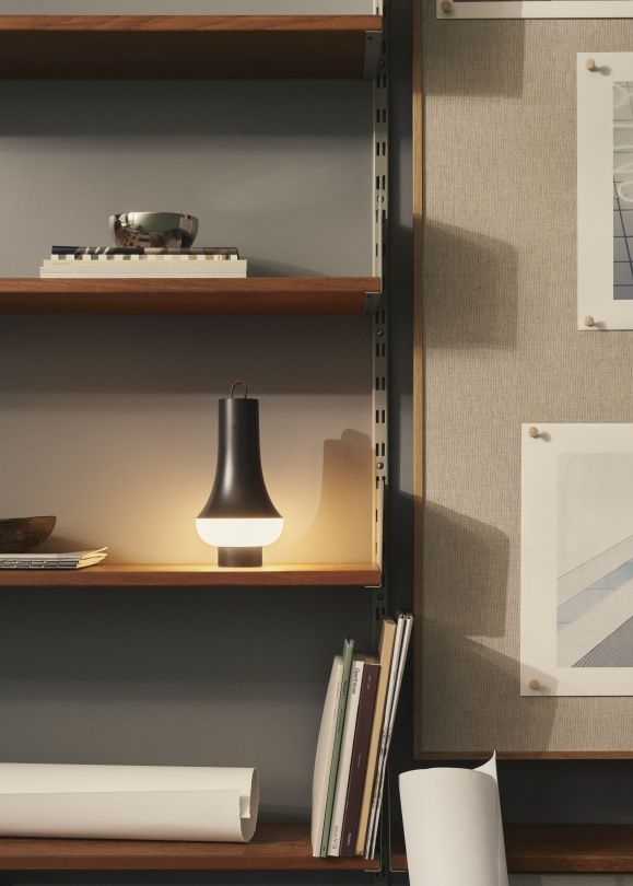 Tomoshi Akkuleuchte von Louis Poulsen in Dunkelbraun auf Holzregal, warmes Licht, modernes Design.