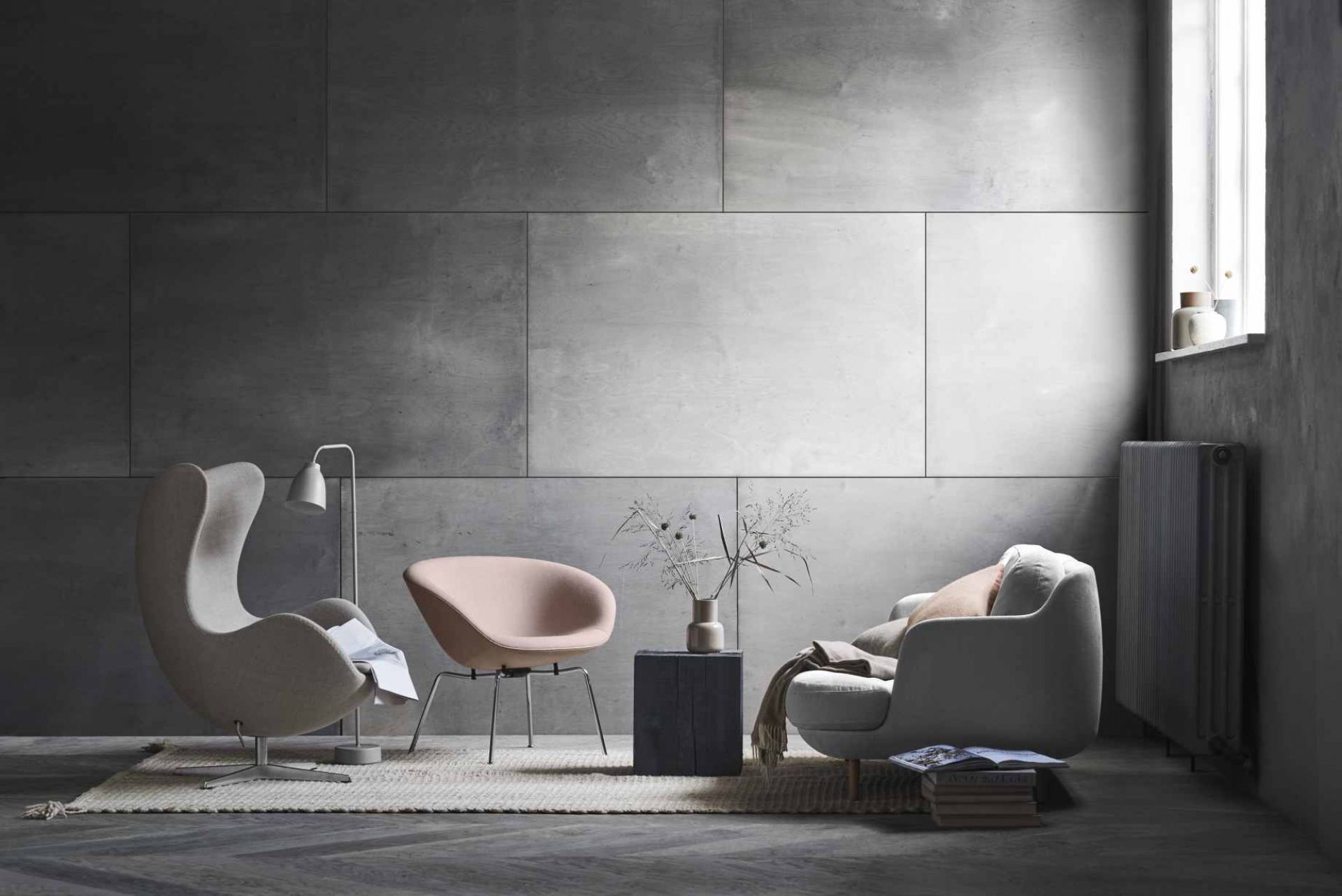 Helles Wohnzimmer mit Fritz Hansen Sesseln und einem Lune Sofa in Weiß vor grauer Wand.