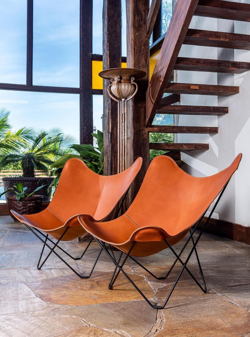 Zwei braune Pampa Mariposa Butterfly Sessel aus Leder mit schwarzem Metallgestell.