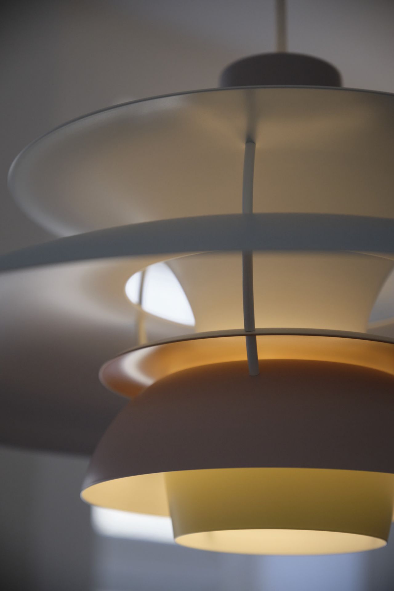Detailaufnahme der Louis Poulsen PH 5 Pendelleuchte in Weiß und Gelb, modernes Design für Wohnraumbeleuchtung.