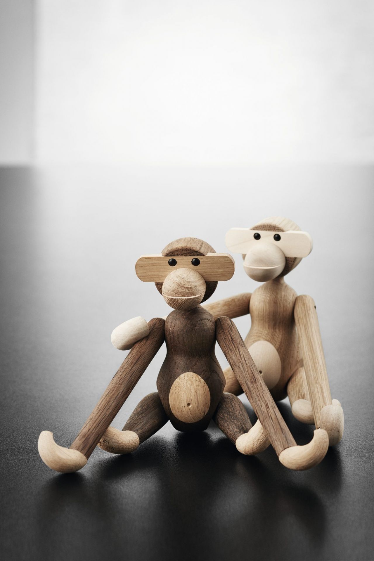 Zwei Kay Bojesen Affen Holzfiguren aus Eiche und Ahorn sitzen nebeneinander.